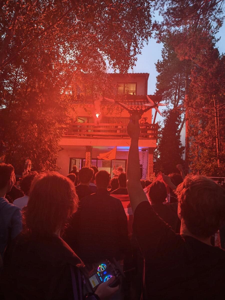 A crowd outside the house at night, lit red